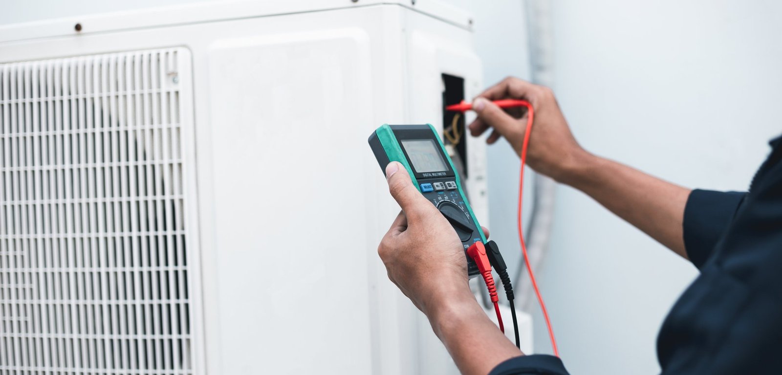 Engineer testing an outdoor unit with a multimeter